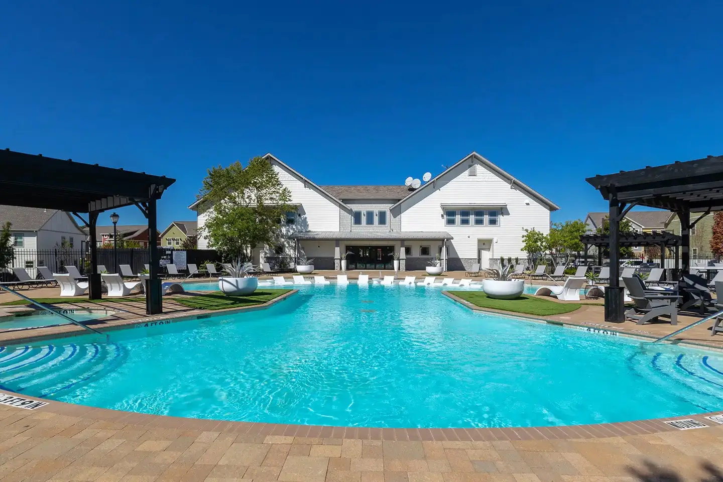 Large pool with various chairs and shaded areas surrounding it.